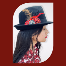 Load image into Gallery viewer, Black Fedora Hat with Feathers and Fabric Flowers on a model with long black hair staring right. The background is red
