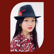 Load image into Gallery viewer, Black Fedora Hat with Feathers and Fabric Flowers on a model with long black hair staring straight. The background is red
