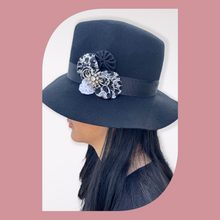 Load image into Gallery viewer, Black Floppy Hat with Leopard Fabric Flowers &amp; Vintage Pin on a model facing left. Pink backgroound
